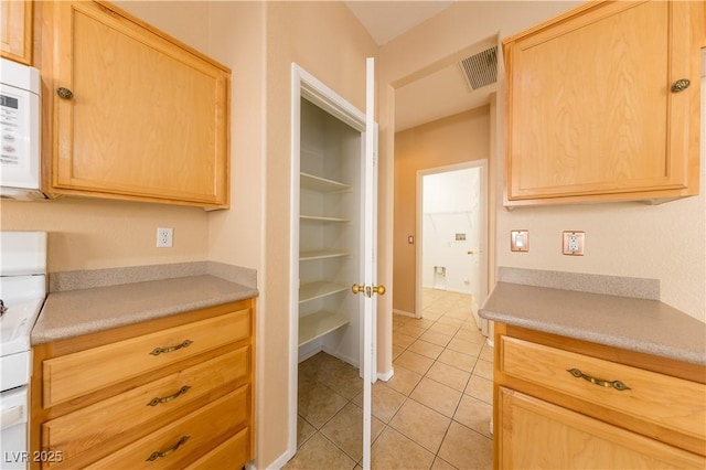 kitchen with light tile patterned flooring, range, and light brown cabinetry