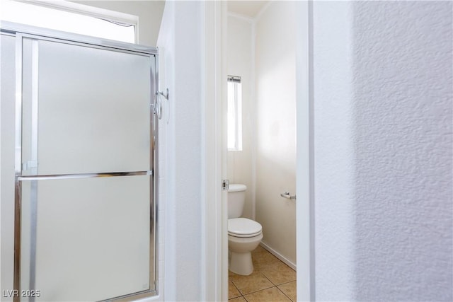 bathroom featuring a shower with door, tile patterned floors, and toilet