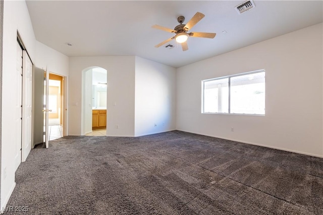 unfurnished bedroom featuring ceiling fan, light carpet, and ensuite bath