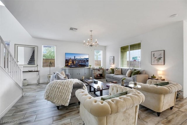 living room featuring an inviting chandelier, light hardwood / wood-style floors, and a wealth of natural light