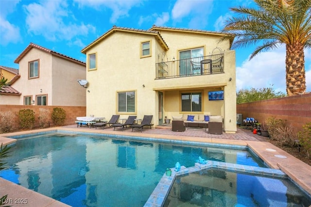 rear view of property with a balcony, an outdoor hangout area, a patio area, and a pool with hot tub