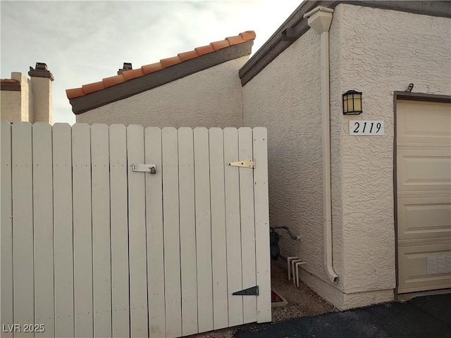 exterior details featuring stucco siding, radiator, and a gate