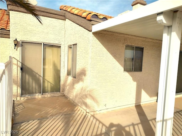 exterior space with stucco siding and a tiled roof