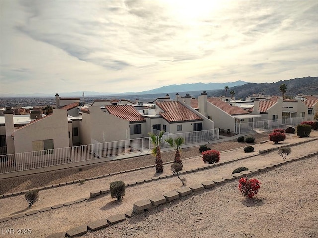 exterior space with a mountain view, a residential view, stucco siding, and fence