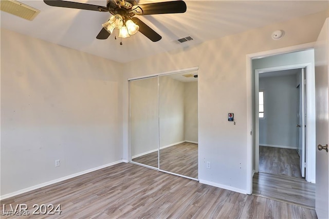 unfurnished bedroom featuring ceiling fan, a closet, and light wood-type flooring