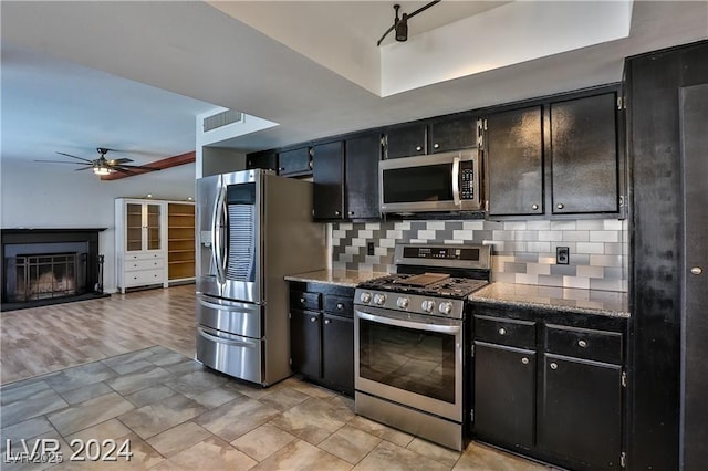 kitchen with ceiling fan, stainless steel appliances, a tray ceiling, and backsplash