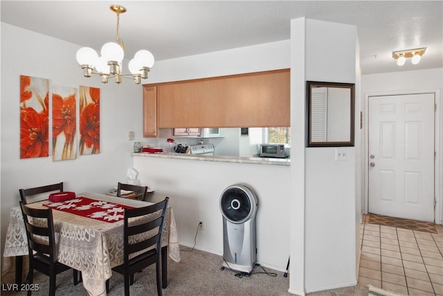 kitchen featuring light tile patterned flooring, an inviting chandelier, kitchen peninsula, pendant lighting, and stove