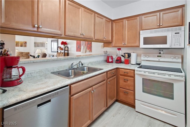 kitchen with white appliances, sink, and light wood-type flooring