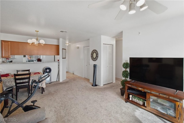 interior space featuring ceiling fan with notable chandelier and light carpet