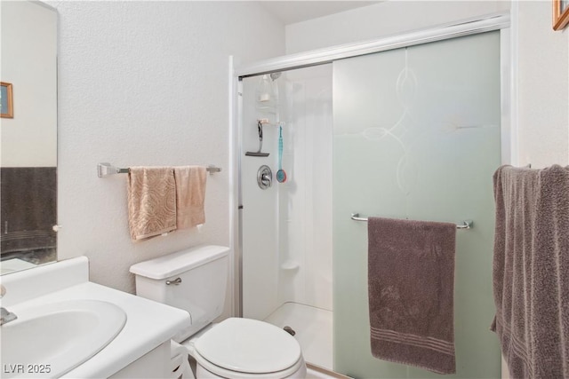 bathroom with vanity, a shower with door, and toilet