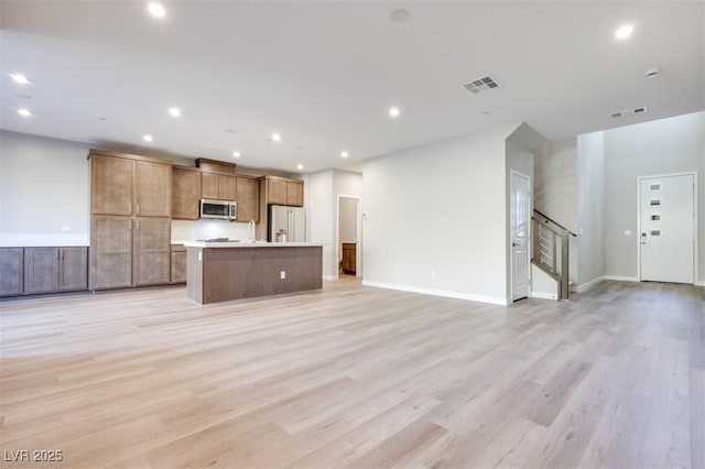 kitchen with a kitchen island, high end fridge, and light hardwood / wood-style floors