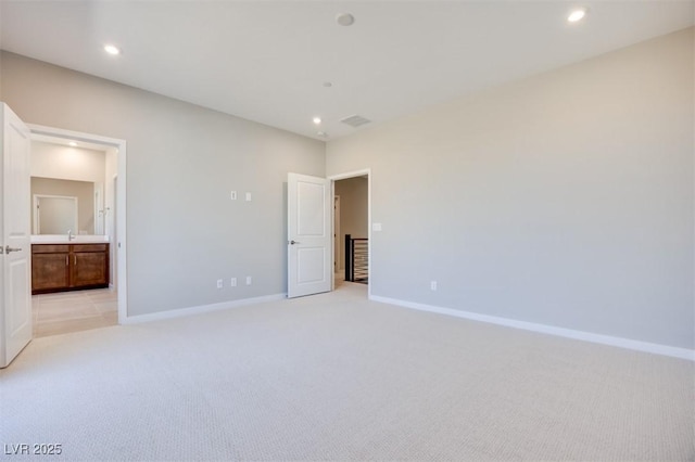 unfurnished bedroom featuring light carpet and connected bathroom