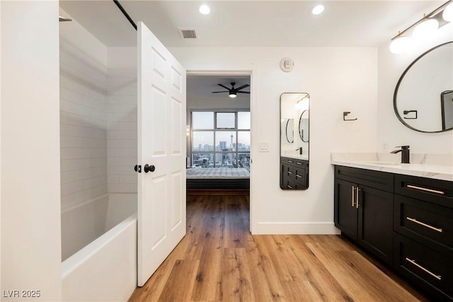 bathroom with hardwood / wood-style flooring, vanity, and bathing tub / shower combination