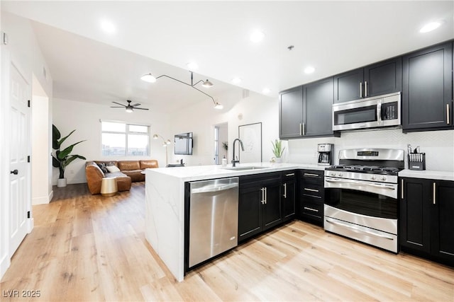 kitchen featuring appliances with stainless steel finishes, sink, light hardwood / wood-style flooring, and kitchen peninsula