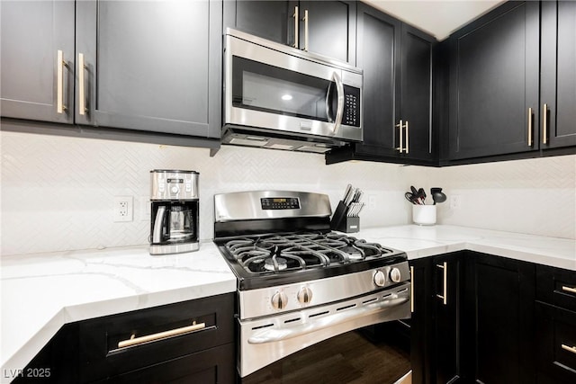 kitchen with stainless steel appliances, tasteful backsplash, and light stone countertops