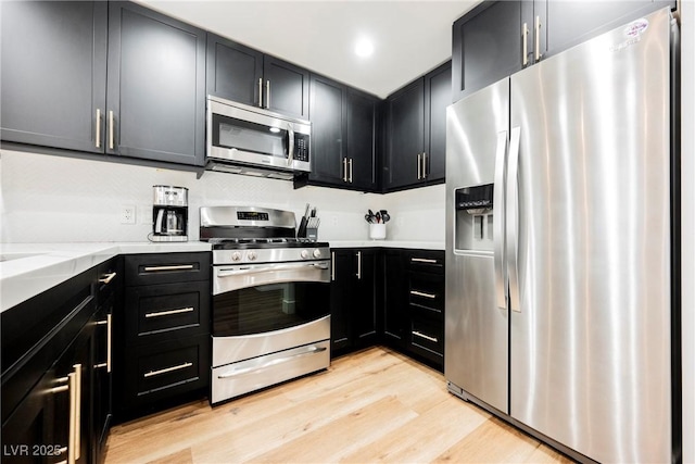 kitchen with light stone countertops, stainless steel appliances, and light wood-type flooring