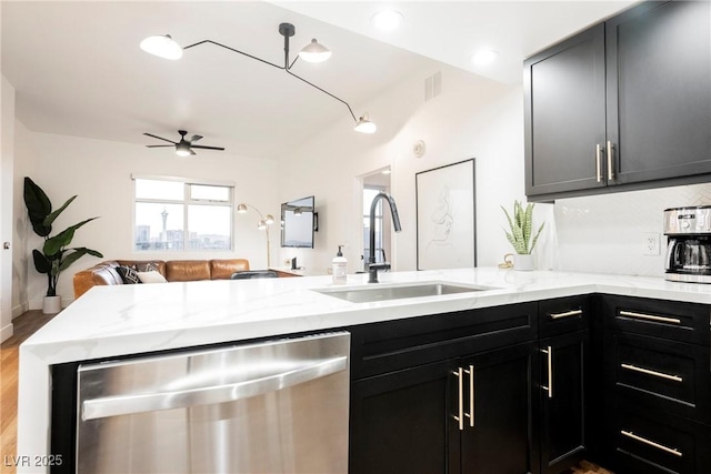 kitchen featuring light stone counters, sink, stainless steel dishwasher, and kitchen peninsula