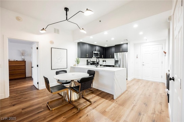 kitchen featuring stainless steel appliances, sink, light hardwood / wood-style flooring, and kitchen peninsula