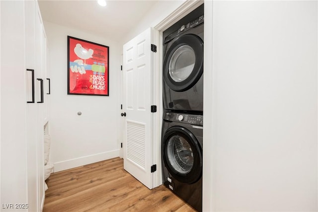 washroom with stacked washer and dryer and light hardwood / wood-style floors