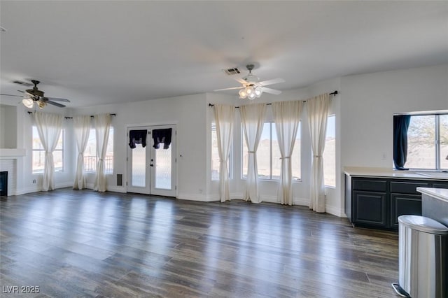 unfurnished living room with plenty of natural light, dark hardwood / wood-style floors, and ceiling fan