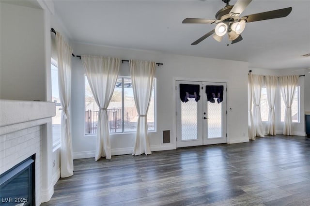 unfurnished living room featuring french doors, ceiling fan, a fireplace, and dark hardwood / wood-style flooring