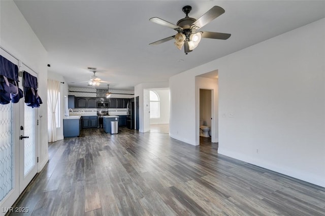 unfurnished living room with dark wood-type flooring, ceiling fan, and sink