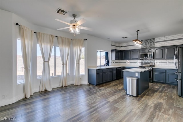 kitchen featuring decorative light fixtures, a center island, appliances with stainless steel finishes, dark hardwood / wood-style flooring, and decorative backsplash