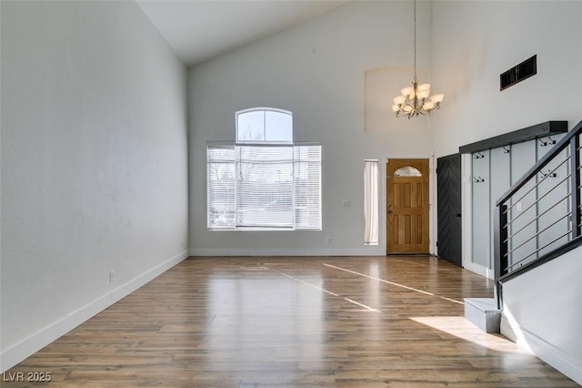 entryway with wood-type flooring, high vaulted ceiling, and an inviting chandelier