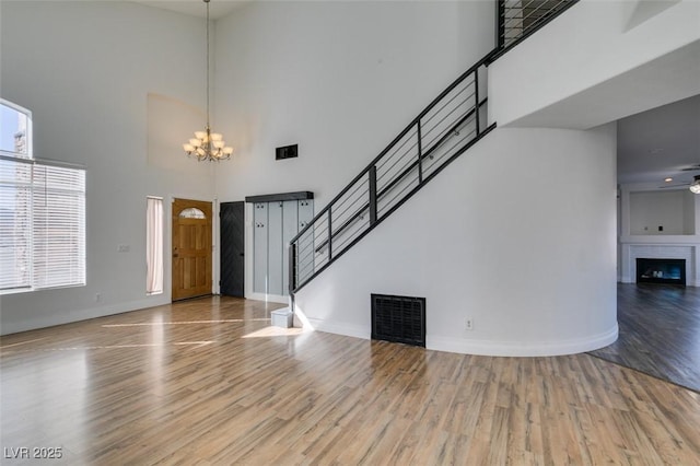 interior space with a towering ceiling, wood-type flooring, and ceiling fan with notable chandelier