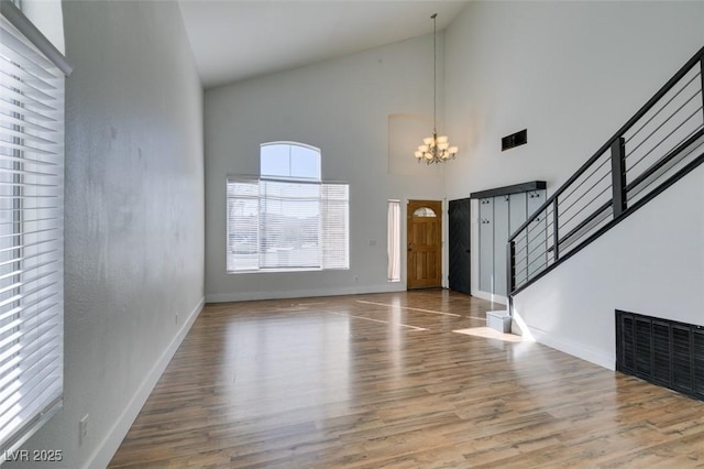 foyer with wood-type flooring, high vaulted ceiling, and an inviting chandelier