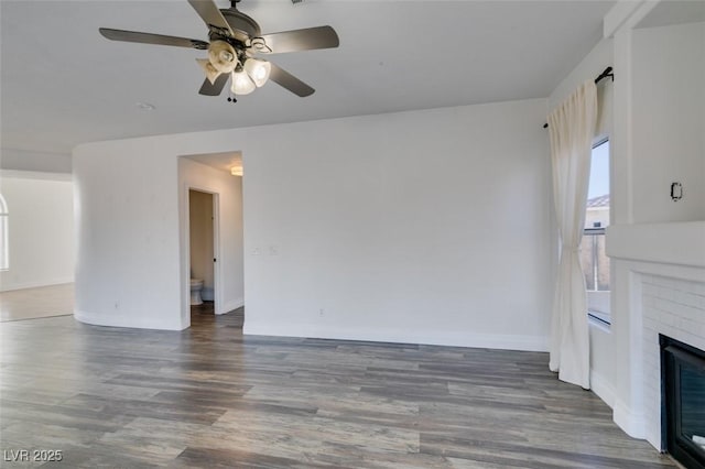 unfurnished living room featuring dark hardwood / wood-style flooring, a brick fireplace, and ceiling fan