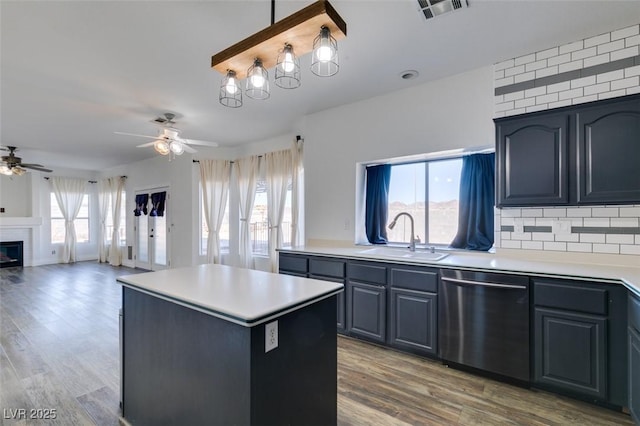 kitchen with sink, hardwood / wood-style flooring, dishwasher, a center island, and tasteful backsplash