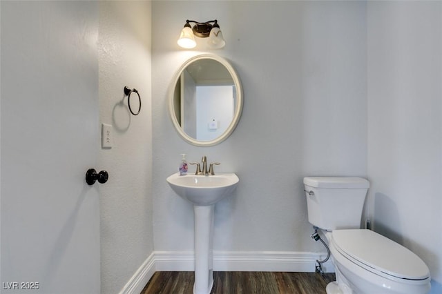 bathroom with wood-type flooring, toilet, and sink