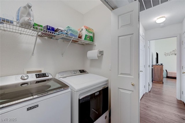 laundry area with washing machine and dryer and light wood-type flooring