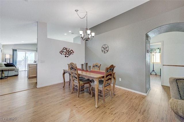 dining area with a notable chandelier, vaulted ceiling, and light hardwood / wood-style floors