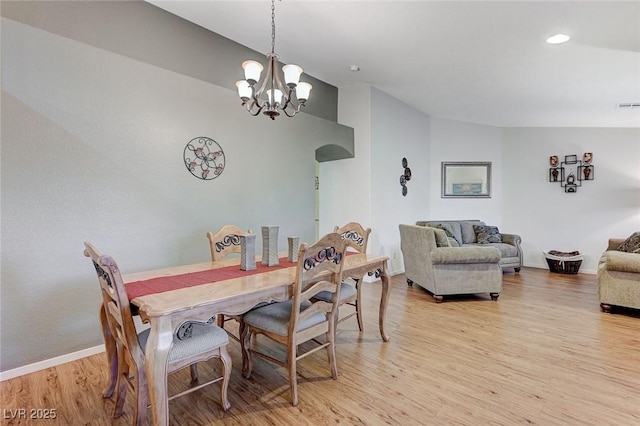 dining space with lofted ceiling, an inviting chandelier, and light hardwood / wood-style floors