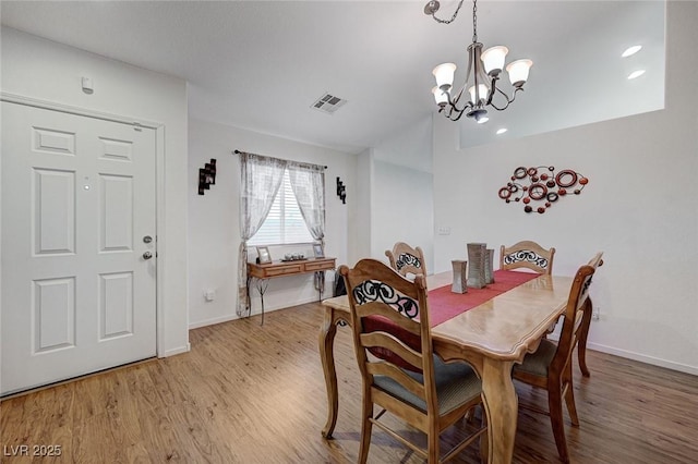 dining space featuring wood-type flooring and an inviting chandelier