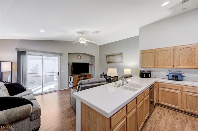 kitchen with sink, ceiling fan, light hardwood / wood-style floors, vaulted ceiling, and kitchen peninsula