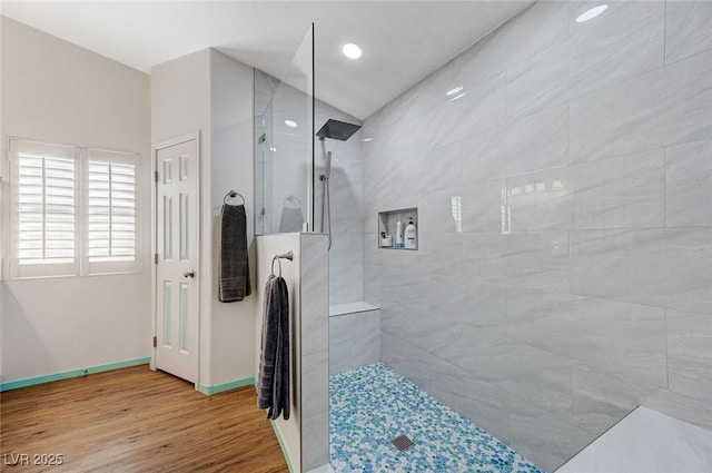 bathroom with a tile shower, wood-type flooring, and lofted ceiling