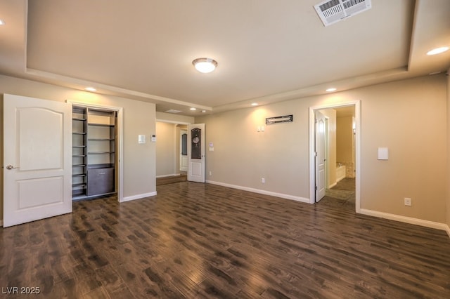 empty room featuring a tray ceiling and dark wood-type flooring