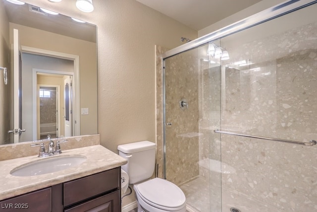 bathroom featuring vanity, a shower with door, and toilet