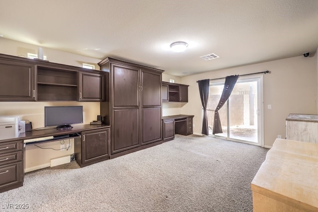 interior space featuring carpet floors, built in desk, and a textured ceiling