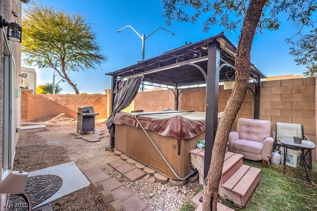 view of patio / terrace with a hot tub, a gazebo, and a grill