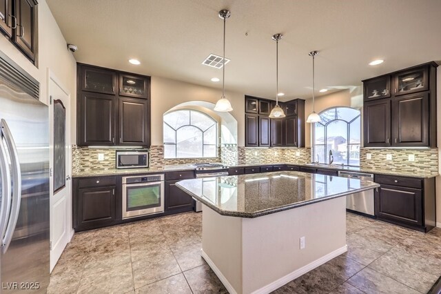 kitchen with dark brown cabinets, stainless steel appliances, a kitchen island, and hanging light fixtures