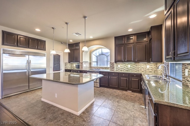 kitchen with hanging light fixtures, stone countertops, appliances with stainless steel finishes, and a center island