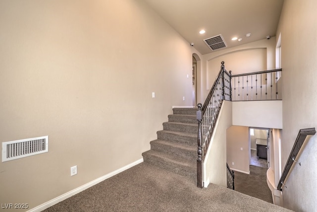 stairway with a high ceiling and carpet floors