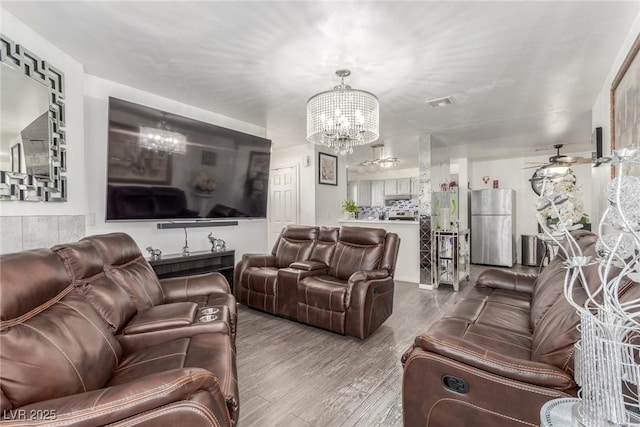 living room with hardwood / wood-style floors and ceiling fan with notable chandelier