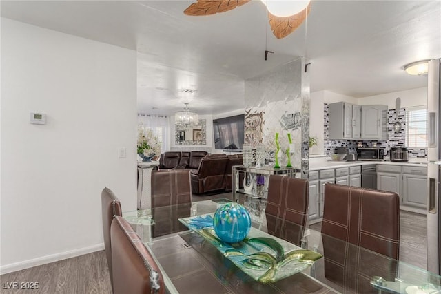 dining room featuring ceiling fan with notable chandelier and dark hardwood / wood-style flooring