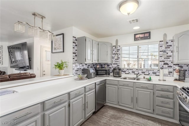 kitchen with appliances with stainless steel finishes, sink, gray cabinetry, and decorative backsplash