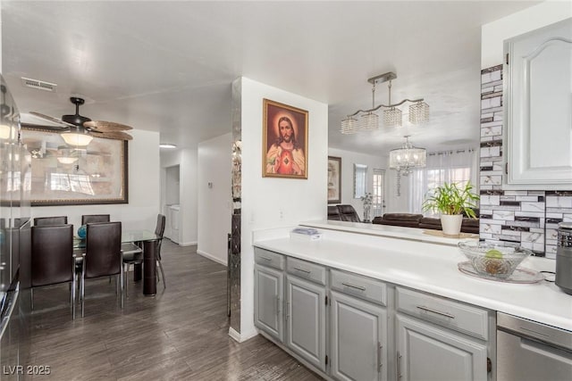 kitchen featuring dark wood-type flooring, hanging light fixtures, gray cabinets, ceiling fan with notable chandelier, and decorative backsplash